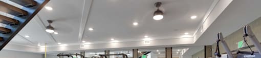 A spacious gym with a variety of equipment and a staircase in the background.