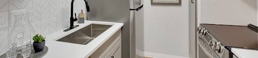 A kitchen with white cabinets and a grey backsplash.