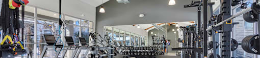 A gym with a variety of equipment including treadmills, weights, and exercise machines.