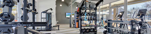 A gym with a variety of equipment including treadmills, weights, and exercise machines.