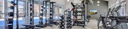 A gym with a variety of equipment including treadmills, weights, and exercise machines.