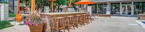 A patio with a bar and seating area under a wooden pergola.