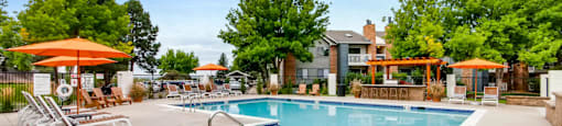 A large swimming pool surrounded by trees and umbrellas.