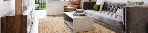 A living room with a grey couch, a coffee table, and a large mirror on the wall.