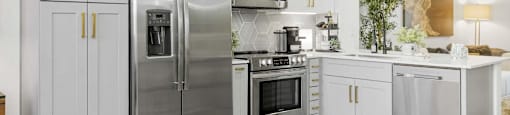 A modern kitchen with a stainless steel refrigerator, microwave, and oven.