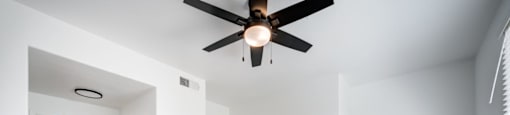 A room with a ceiling fan and wooden flooring.