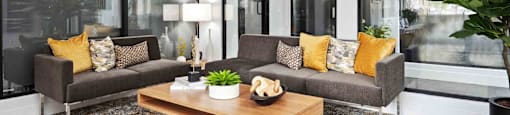 A living room with a grey couch, a wooden coffee table, and a large mirror on the wall.