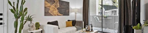A living room with a white couch, a coffee table, and a cactus plant.