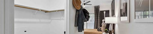 A hallway with a bench and a coat rack.