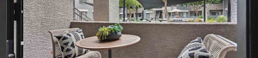 A patio with a table and two chairs with a view of apartment buildings.