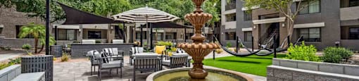 A fountain in the middle of a courtyard surrounded by chairs and umbrellas.