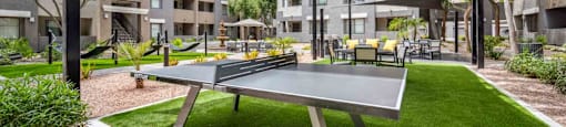 A ping pong table is in the middle of a grassy area.