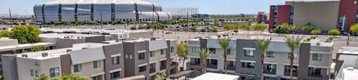 A modern building with a circular courtyard in the foreground and a large stadium in the background.