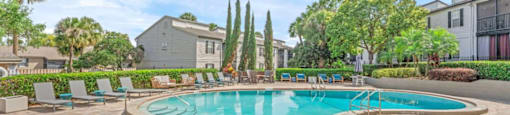 A swimming pool surrounded by a brick patio and lounge chairs.