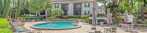 A pool surrounded by chairs and umbrellas with a building in the background.