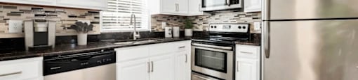 A modern kitchen with stainless steel appliances and white cabinets.