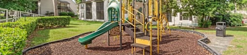 A playground with a green slide and yellow swings.
