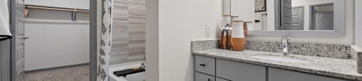 A bathroom with a sink, mirror, and bathtub.