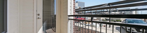 A balcony with a metal railing and a view of the street below.