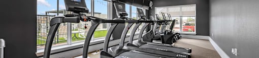 A row of TRUE treadmills are lined up in a gym.