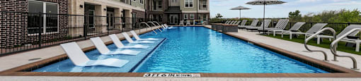 A pool surrounded by chairs and buildings.
