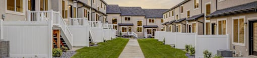 A long concrete walkway leads between a row of houses.
