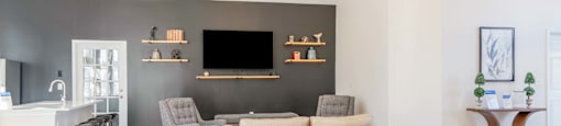 A living room in a clubhouse with a grey couch and a wooden floor.