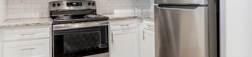 A kitchen with a stainless steel refrigerator, microwave, oven, and tiled backsplash.