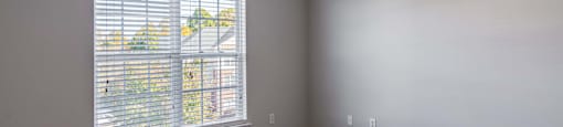 A room with a ceiling fan and a window with blinds.