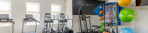 A gym with treadmills, exercise balls, and ropes.