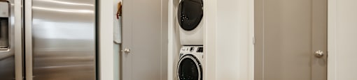A modern kitchen with a stainless steel refrigerator and a washing machine in the laundry room.