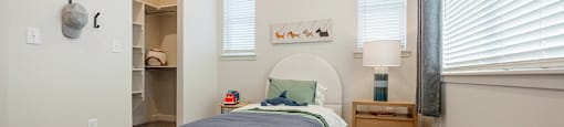 A bedroom with a bed, nightstand, and window.
