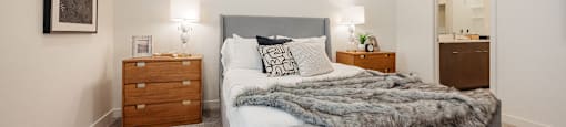 A bedroom with a large bed and a nightstand with a lamp.
