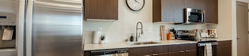 A modern kitchen with a stainless steel refrigerator and wooden cabinets.