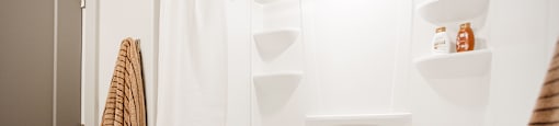 A white bathroom with a towel hanging on the door.