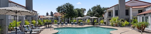 A large outdoor swimming pool surrounded by lounge chairs and umbrellas.