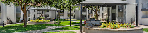 A gazebo is in the middle of a grassy area with a concrete walkway leading to it.