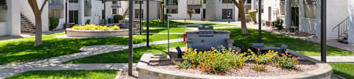 A sunny day at a park with a pavilion and a fire pit.