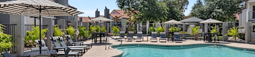 A large outdoor swimming pool surrounded by lounge chairs and umbrellas.