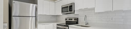 A modern kitchen with white cabinets and stainless steel appliances.