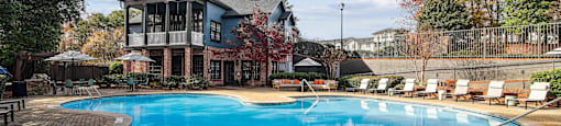 A large outdoor swimming pool surrounded by a brick patio.