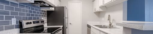 A kitchen with white cabinets and a black refrigerator.
