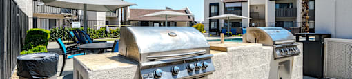 A large outdoor grill is in the foreground of a residential area.