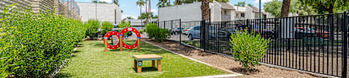 A small garden with a bench and a red sculpture.
