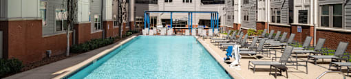a swimming pool with lounge chairs in front of an apartment building