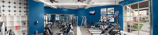 a gym with treadmills and other exercise equipment in a building with blue walls