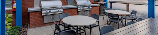 a patio with tables and barbecue grills and tables and chairs