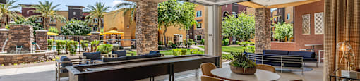 a patio with a table and chairs and a pool in the background