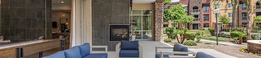 a patio with blue couches and chairs and a fireplace