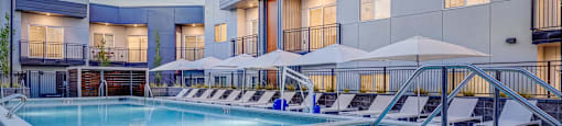 A large outdoor swimming pool with lounge chairs and umbrellas.